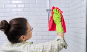 woman cleaning Houston frameless glass showers with cloth