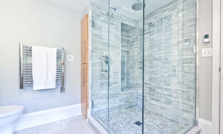 custom frameless glass shower with grey tile and white towels